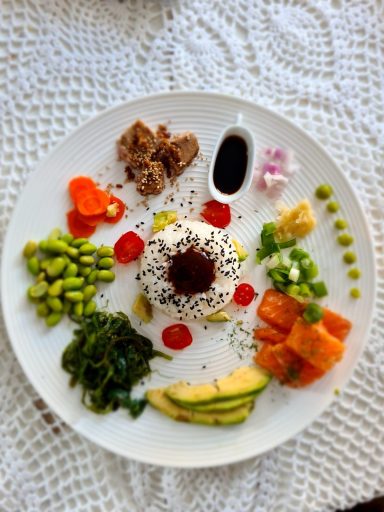 Een kleurrijk bord met sushi, groenten, fruit en sauzen, mooi gepresenteerd.